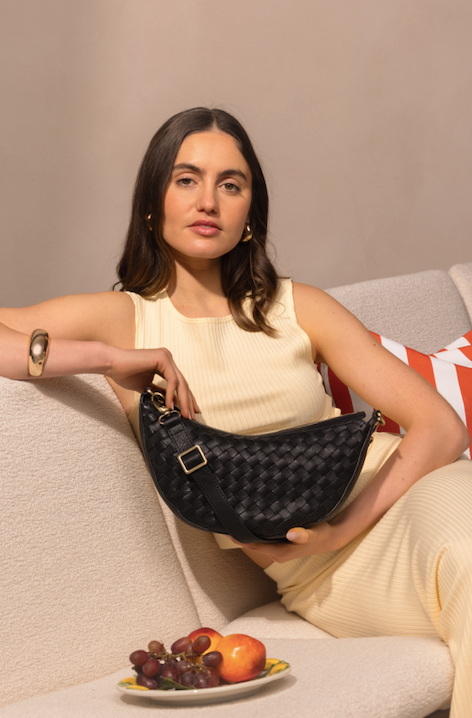 Woman holding O My Bag Leo Black Woven Soft Grain Leather bag, styled in a chic setting with fresh fruits.