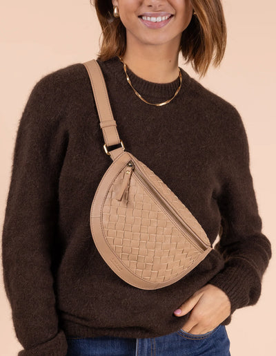 O My Bag Ray Bumbag in sand woven leather, styled as a crossbody bag on a model with a brown sweater.